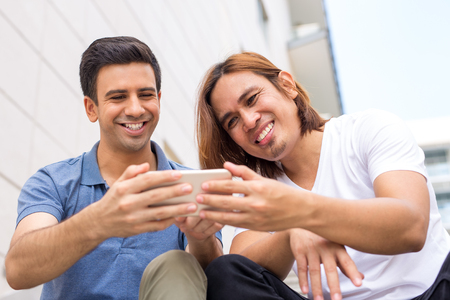 Two Happy Young Men Browsing on Smartphoneの写真素材