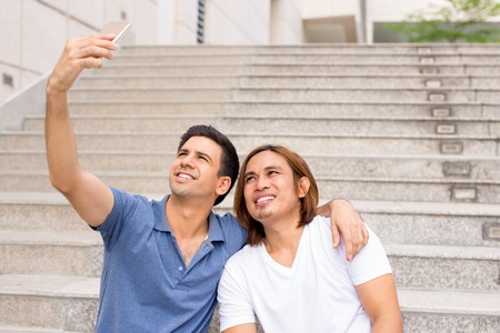 Two Happy Men Taking Selfie on Outdoor Stairwayの写真素材