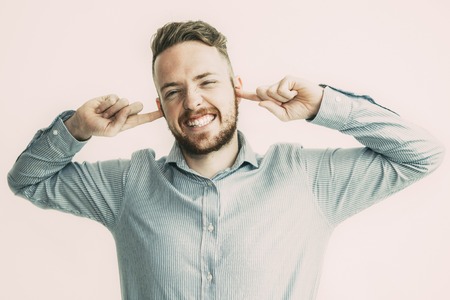 Man Grinning and Stopping Ears With Fingersの写真素材