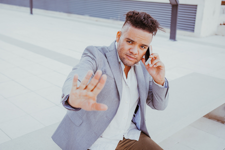 Displeased businessman talking on phone outdoorsの写真素材