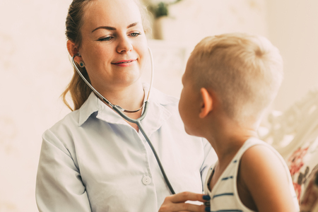 Smiling young female doctor examining little boyの写真素材