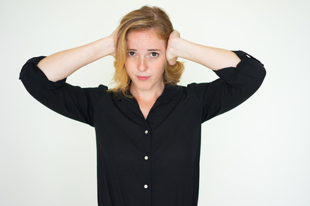 Annoyed young woman covering ears from loud noise