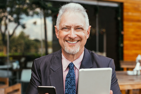 Happy Boss Using Tablet and Smartphone Outdoorsの写真素材
