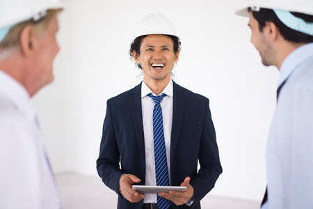 Excited Asian inspector talking to colleaguesの写真素材