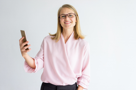 Happy successful lady using video call on phone while talking to colleague. Smiling pleased businesswoman in eyeglasses using modern device. Opportunities with technology conceptの写真素材