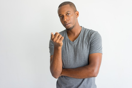 Serious uncertain handsome African guy pointing at camera while asking question. Misunderstanding young man with beard wearing t-shirt looking at camera. Problem conceptの写真素材