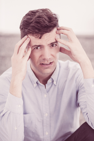 Stressed businessman suffering from headache and looking at camera. Portrait of frustrated man having stress or pain. He holding head with hands. Business conceptの写真素材