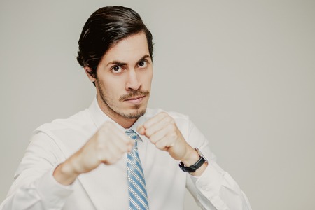 Portrait of aggressive young Caucasian businessman wearing shirt and tie boxing and looking at camera. Competition conceptの写真素材