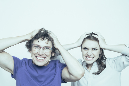 Senior and young women holding head in handsの写真素材