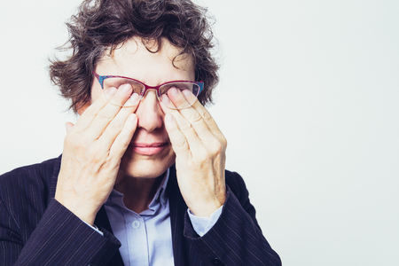 Tired businesswoman rubbing eyes behind glassesの写真素材