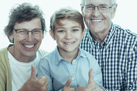 Joyful grandson and grandparents showing thumb up