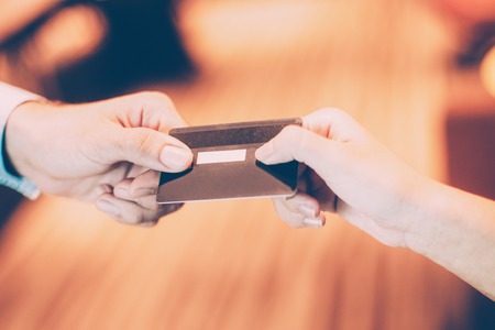 Male hand giving credit or debit card to female cashier for payment at shop or cafeの写真素材
