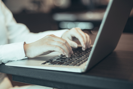 Young businesswoman sitting at table in office and using laptop. Female student surfing internetの写真素材