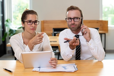 Business colleagues pointing at something and using devices.