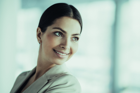 Closeup portrait of smiling beautiful middle-aged business woman wearing jacket, turning round and looking away. Side view.の写真素材
