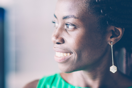 Close-up of face of young African American woman wearing earring, looking away and smilingの写真素材