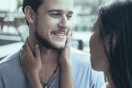 Closeup of Asian woman embracing neck of smiling boyfriend. Woman is back to camera.の写真素材