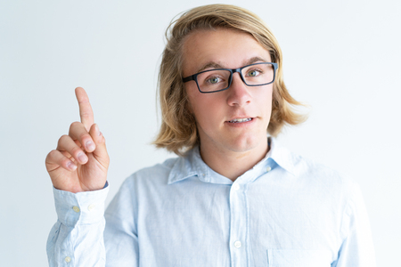 Portrait of confident guy in glasses showing attention gesture. Caucasian student having idea. Attention or idea conceptの写真素材