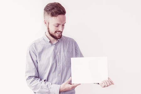 Portrait of bearded young Caucasian businessman wearing shirt demonstrating advertisement and smilingの写真素材