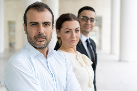 Serious confident company representatives. Portrait of unsmiling businessman and his colleague standing behind. Company owner conceptの写真素材