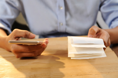 Closeup of person calculating or paying bills. Woman using smartphone. Online payment concept. Cropped view.の写真素材