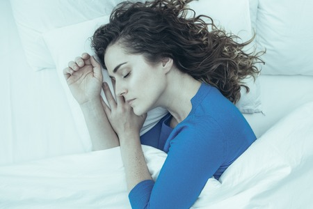 Closeup portrait of middle-aged beautiful woman sleeping in bed in bedroom. Top view.の写真素材