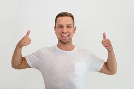 Smiling man showing both thumbs up and looking at camera. Handsome guy advertising something. Promotion concept. Isolated front view on white background.の写真素材