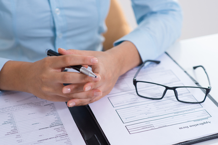 Closeup of boss reading filled application form. Business person sitting at desk. Recruitment...