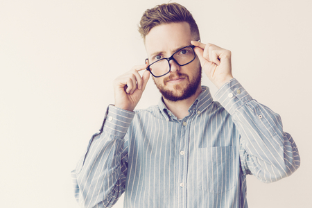 Portrait of attractive shocked young man wearing glasses incorrectly. Businessman discovering new unexpected way for development. Good or bad news concept.の写真素材