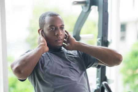 Focused black man doing sit ups in gym. Young guy wearing t-shirt and training with window in...