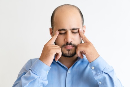 Pensive man touching head with fingers and concentrating. Attractive guy thinking with his eyes...