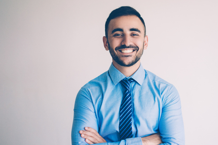 Portrait of confident young man with arms crossed smiling at camera. Best manager posing for picture to wall of fame. Business success conceptの写真素材