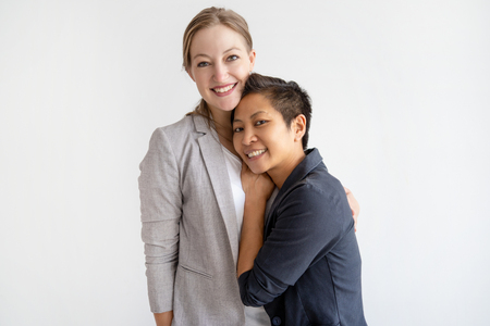 Happy multi-ethnic lesbian couple hugging. Homosexual women. Lesbian couple concept. Isolated front view on white background.の写真素材