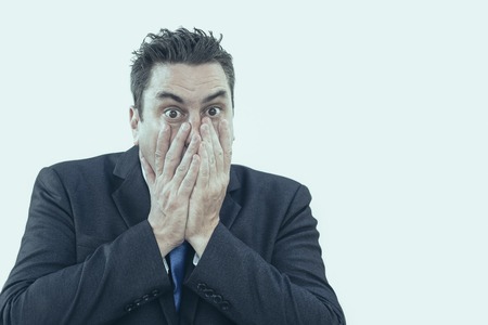 Shocked scared businessman covering mouth with hands and looking at camera. Amazed male manager having troubles. Surprised man conceptの写真素材
