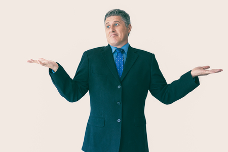 Portrait of confused mature Caucasian businessman wearing black jacket and necktie standing and shrugging shoulders. Ignorance and confusion conceptの写真素材