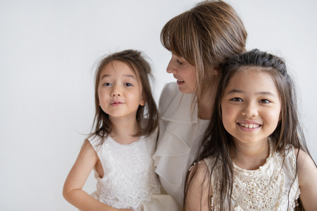 Happy Caucasian mum and little daughters spending time together. Pretty woman admiring one daughter with second daughter smiling at camera. Family admiration concept.の写真素材
