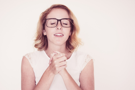 Calm inspired woman closing eyes to make wish. Focused woman in glasses praying. Spirituality conceptの写真素材
