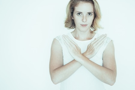 Serious displeased young businesswoman crossing hands showing stop gesture. Confident lady looking at camera and making rejection sign. Decline conceptの写真素材