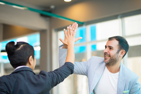 Positive Latin and Asian managers high fiving. Business team celebrating success. Success concept