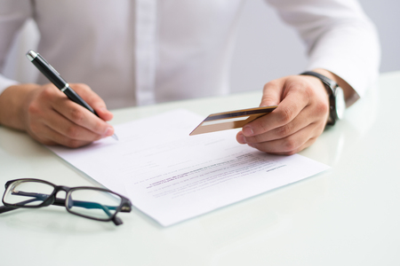 Close-up of man filling information about credit card in bank. Unrecognizable businessman changing credit card and signing agreement with banking company. Finance conceptの写真素材