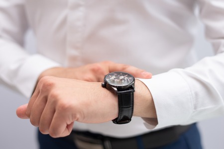 Close-up of businessman checking time with wristwatch. Caucasian executive waiting for client being late. Time and punctuality conceptの写真素材