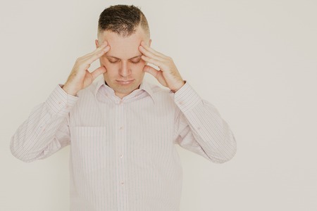 Portrait of concentrated mid adult Caucasian businessman wearing striped shirt touching head. Man...