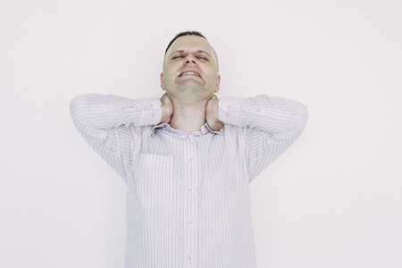 Annoyed young male employee tired from routine. Exhausted businessman massaging neck after work. Emotional stress conceptの写真素材