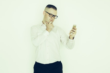 Pensive serious businessman reading sms on smartphone and thinking of strategy. Enterprising male manager corresponding with client via online messenger. Connection conceptの写真素材
