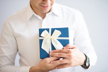 Closeup of positive man embracing gift box. Person receiving gift. Gift concept. Isolated cropped view on grey background.の写真素材