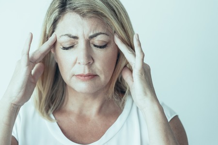 Annoyed woman feeling pain touching temples while trying to concentrate. Puzzled businesswoman having problems. Migraine conceptの写真素材