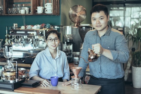 Modern Asian couple making best coffee in town. Content confident young family running own business. Coffee roasting house conceptの写真素材