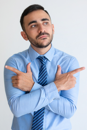 Puzzled young businessman pointing with finger guns in different directions. Sad unsure male manager with beard deep in thoughts. Dilemma conceptの写真素材