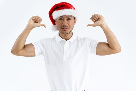 Confident Asian man wearing Santa hat and pointing at himself. Self-assured attractive guy looking at camera. Christmas promotion concept. Isolated front view on white background.の写真素材