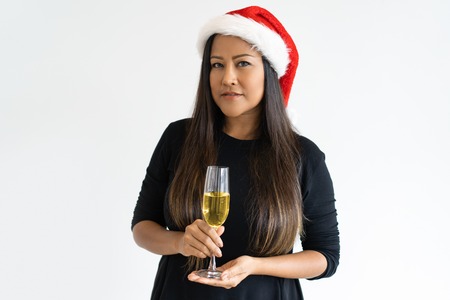 Portrait of confident businesswoman with champagne flute. Mid adult Asian woman celebrating New Year. Christmas and New Year party conceptの写真素材